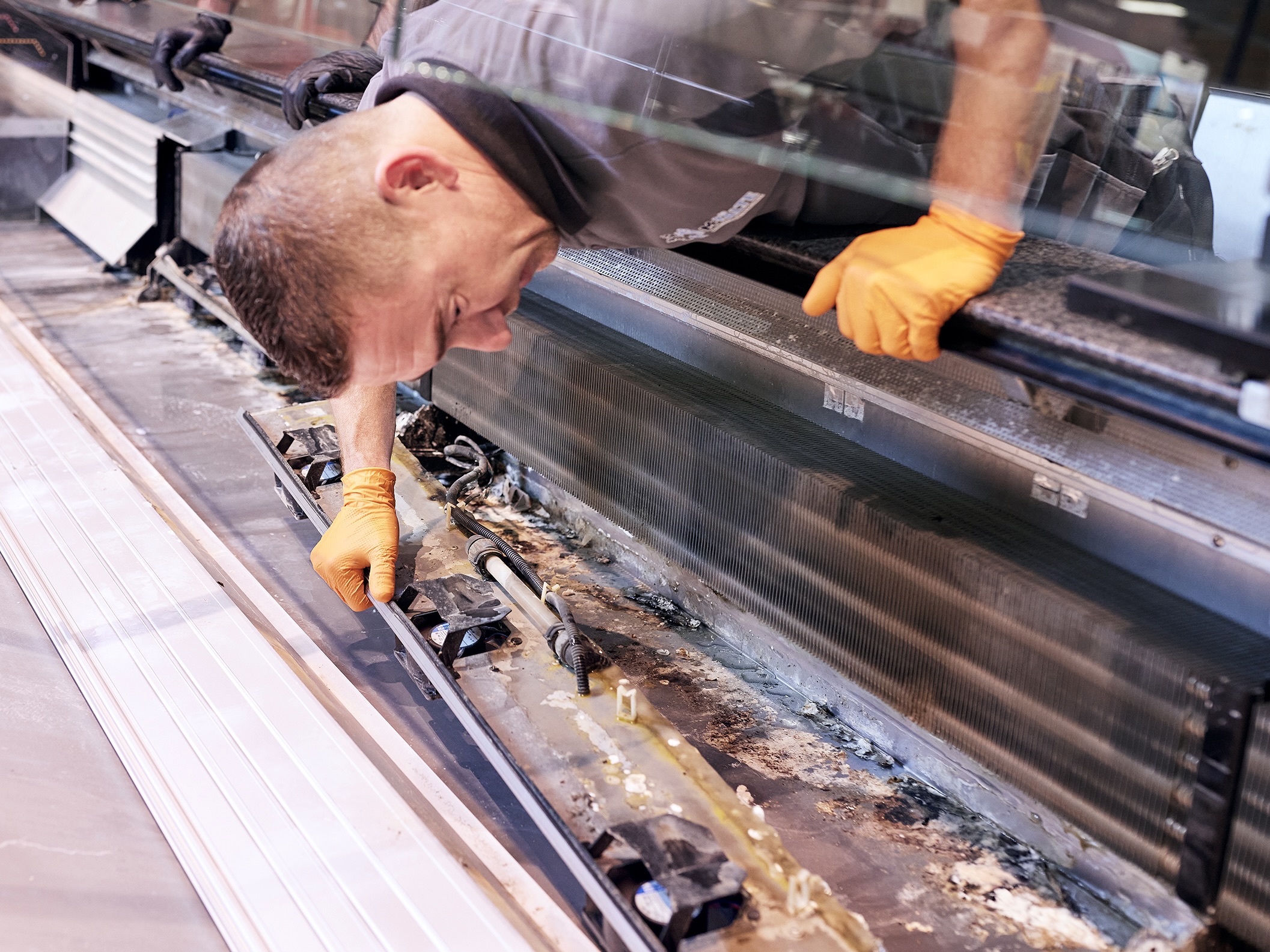 M-KÄLTE Techniker bei Arbeiten an einem Kühlmöbel im Lebensmittelmarkt